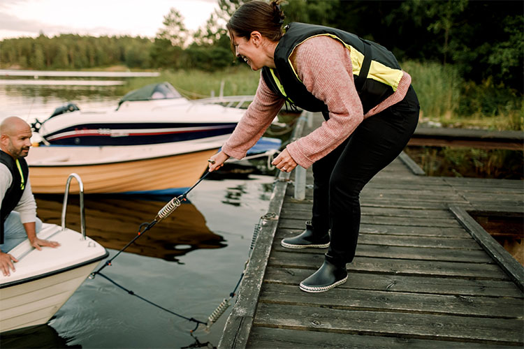 부두에 서서 작은 보트를 끄는 남자를 돕는 여자